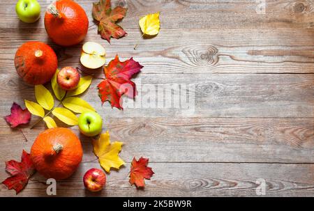 Herbstrand aus Äpfeln, Kürbis und abgefallenen Blättern auf altem Holztisch. Halloween oder Thanksgiving-Tag-Konzept. Thanksgiving Kürbis mit Früchten. Fru Stockfoto