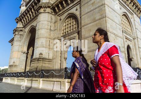 Mumbai, Maharashtra, Indien : Indische Frauen gehen am Gateway of India monumentalen Bogen vorbei, der zwischen 1913 und 1924 im indo-sarazenischen Stil erbaut wurde. Stockfoto