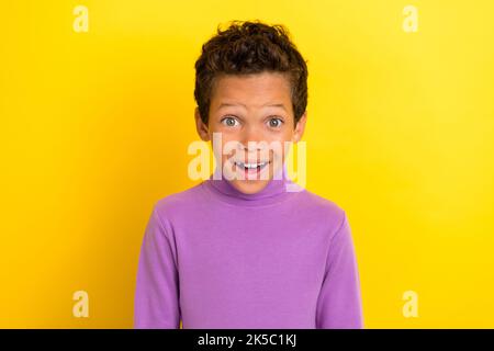 Foto-Porträt von charmanten kleinen Jungen aufgeregt Lächeln kann nicht glauben, gewinnen Lotterie tragen trendige violette Kleidungsstück auf gelbem Hintergrund isoliert Stockfoto