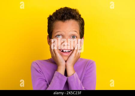 Foto von staunenden Schüler strahlend Lächeln Arme berühren Wangenknochen isoliert auf gelbem Hintergrund Stockfoto