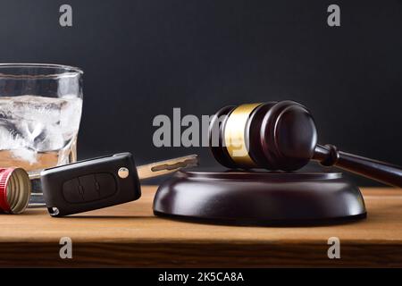 Gavel, Autoschlüssel und Glas mit Alkohol auf Holztisch und schwarzem isolierten Hintergrund. Konzeptstudie für das Fahren mit Alkoholsatz nicht erlaubt. . Stockfoto