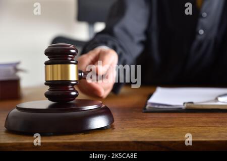 Detail eines Richters, der das Urteil gefällt, indem er mit dem Gavel auf einen Holztisch trifft. Vorderansicht Stockfoto