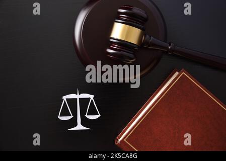 Objekte Symbole der Gerechtigkeit wie Waagen-Keule und Gesetzbuch auf schwarzem Tisch. Draufsicht Stockfoto