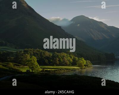 Die Sonne erleuchtet Bäume am Ufer des Wastwater im Seengebiet Stockfoto