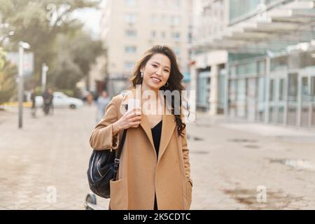 Lifestyle-Porträt hübsche asiatische kasachische Frau mit brillantem Lächeln auf der Straße Stockfoto