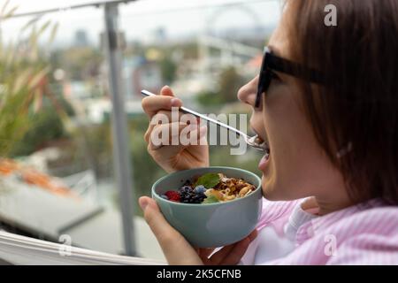 Junge Frau, die Chia-Pudding mit Nüssen und Beeren isst Stockfoto