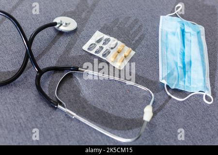 Apotheke Hintergrund auf einem weißen Tisch. Tabletten auf einem weißen Hintergrund. Pillen. Medizin und gesund. Nahaufnahme von Kapseln. Stethoskop auf weißem Holz- Stockfoto