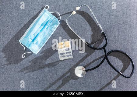 Apotheke Hintergrund auf einem weißen Tisch. Tabletten auf einem weißen Hintergrund. Pillen. Medizin und gesund. Nahaufnahme von Kapseln. Stethoskop auf weißem Holz- Stockfoto