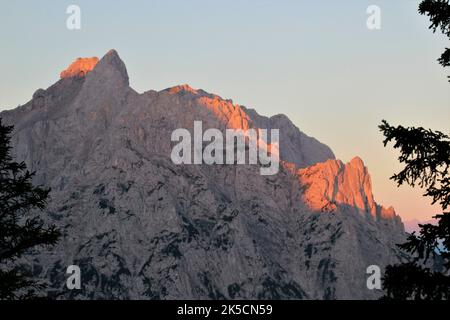 Morgenwanderung zum Wörnersattel, Sonnenaufgang am Karwendel, die ersten Sonnenstrahlen treffen auf die Viererspitze im Bild rechts, die westliche Karwendelspitze im Bild links, blauer Himmel, Karwendelgebirge, Mittenwald, Oberbayern, Bayern, Werdenfels, Deutschland, Europa, Alpenwelt Karwendel Stockfoto