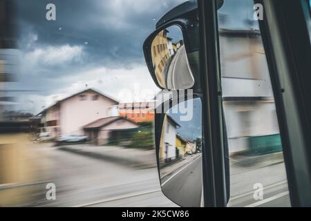 Blick auf die Straße vom Fahrerhaus eines fahrenden Lkw durch das Glas und den Rückspiegel Stockfoto