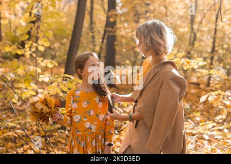 Besorgt Mutter auf beleidigte kleine Tochter nach Familie Streit im Herbst Natur suchen, Mutter und weibliches Kind leiden Missverständnisse und Stockfoto