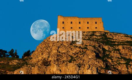 Italien, Sizilien, Trapani, Mons Erix, Altliches Erice, Morgenlicht, blauer Himmel, Festungsgebäude erhebt sich auf dem Berg, dahinter der untersteigende Vollmond Stockfoto