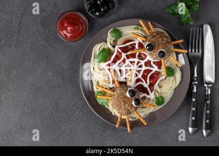 Koteletts sehen aus wie Spinnen mit Olivenaugen und Trinkhalmen, serviert mit Spaghetti-Nudeln und Tomatensauce. Halloween-Frühstück, Copy Space Stockfoto