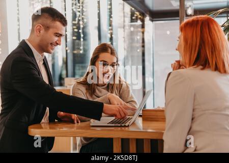 Eine Gruppe von Freunden hängt in einem Café, und unter ihnen ist ein Tablet. Stockfoto