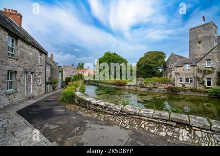 An einem Sommertag in Swanage, Dorset, Großbritannien, befindet sich ein Mühlenteich, Hütten und die Kirche St. Mary the Virgin Stockfoto