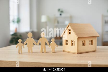 Nahaufnahme von Holzfiguren der Familie mit Kindern und Modell eines kleinen einstöckigen Hauses. Stockfoto