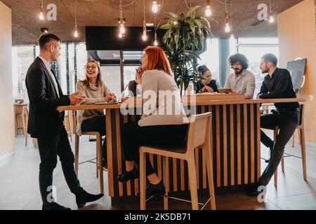 Eine Gruppe von Freunden hängt in einem Café, und unter ihnen ist ein Tablet. Stockfoto
