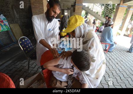 Peshawar, Pakistan. 06. Oktober 2022. Ein Student erhält am 6. Oktober 2022 während einer Impfkampagne an der Peshawar-Modellschule Warsak Road in Peshawar, Pakistan, einen Typhus-Impfstoff. Nach Angaben des Gesundheitsministeriums werden alle Kinder im Alter zwischen 9 Monaten und 15 Jahren in der ersten Phase der Kampagne geimpft. (Foto: Hussain Ali/Pacific Press/Sipa USA) Quelle: SIPA USA/Alamy Live News Stockfoto