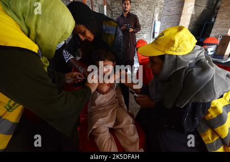 Peshawar, Pakistan. 06. Oktober 2022. Ein Student erhält am 6. Oktober 2022 während einer Impfkampagne an der Peshawar-Modellschule Warsak Road in Peshawar, Pakistan, einen Typhus-Impfstoff. Nach Angaben des Gesundheitsministeriums werden alle Kinder im Alter zwischen 9 Monaten und 15 Jahren in der ersten Phase der Kampagne geimpft. (Foto: Hussain Ali/Pacific Press/Sipa USA) Quelle: SIPA USA/Alamy Live News Stockfoto