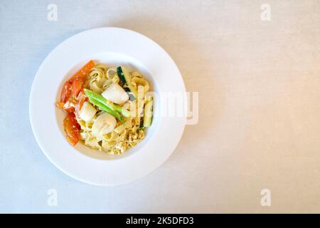 Gebratene Nudeln mit Jakobsmuscheln und Gemüse. Es ist eine gemeinsame hausgemachte Küche in vielen asiatischen Ländern wie China, Taiwan und Thailand. Stockfoto