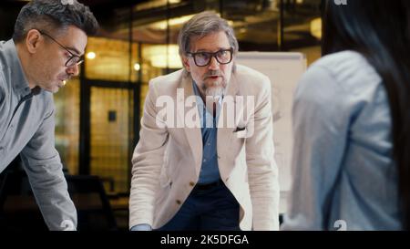 CEO spricht, leitet Geschäftstreffen im Bürokonferenzraum. Diverse Team von Büromitarbeitern diskutieren Geschäftsstrategie des Unternehmens, arbeiten an Startup-Projekt. Teamarbeit und Brainstorming Stockfoto