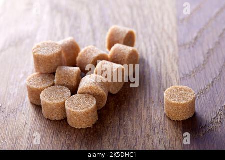 Brauner runder Zucker bildet sich auf einem alten dunklen Holzschneidebrett - Nahaufnahme Stockfoto