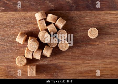 Brauner runder Zucker bildet sich auf einem alten dunklen Holzschneidebrett - Draufsicht Stockfoto