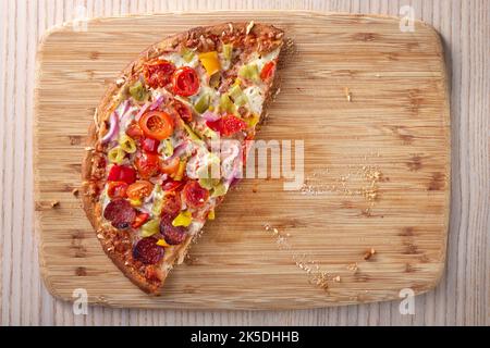 Pizza mit Salami, Pfefferoni, Tomaten und Zwiebeln auf einem Tisch, Nahaufnahme der vertikalen Ansicht von oben Stockfoto