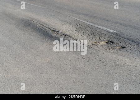 Deformierte Asphaltoberfläche mit Schlaglöchern, die durch schwere überlastete Lkw auf der Autobahn verursacht werden Stockfoto