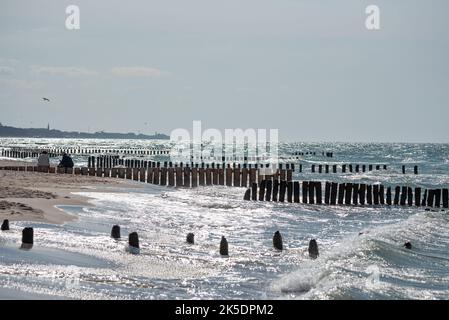 Hölzerner Wellenbrecher und raues Meer. Wellen auf See stürzen gegen die hölzernen Säulen des Wellenbrechers. Stockfoto