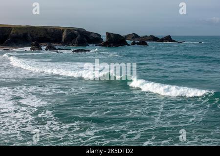 Blick über Porth Beach in Richtung Newquay mit brechenden Wellen und Felsformationen in Cornwall, England, Großbritannien Stockfoto
