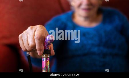 Nahaufnahme der Hände einer älteren Frau, die einen Gehstock hält. Detail der alten kaukasischen Oma Hand halten Griff von Stock. Konzept für ältere Menschen. Stockfoto