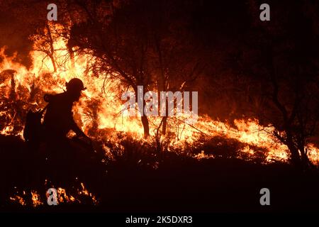 Ein Feuerwehrmann der Fricksburg Task Force des Texas State Forrest Service geht über die Gratlinie eines kontrollierten „Burn-out“, der begonnen wurde, das Gebiet eines großen Waldbrands am 9. April 2022 auf dem Gebiet der Abrisszone der Joint Base San Antonio - Camp Bullis zu verwalten. Das JBSA-Camp Bullis umfasst mehr als 27.000 Acres an Ranges, Trainingsgebieten und Wildgebieten auf der Nordseite von San Antonio und ist ein entscheidender Schulungsort für Servicemitarbeiter der Joint Base San Antonio. Eine optimierte/verbesserte Version eines USAF-Fotos. Kredit: USAF/B.Boisvert Stockfoto