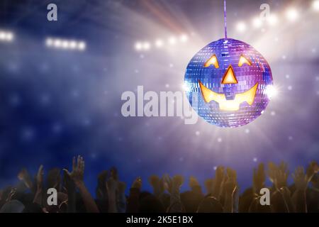 Halloween Disco Party in einem Nachtclub. Glühender Jack Laterne Disco Ball. Eine Gruppe von Freunden tanzt und feiert Urlaub. Menge bei lustigen Feiern. Stockfoto