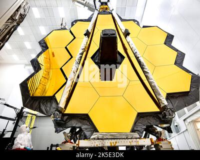 Der Primärspiegel des James Webb Space Telescope (JWST) wurde für Tests in einem Reinraum im Johnson Space Center der NASA in Houston vorbereitet, wo er seinen letzten kryogenen Test durchlaufen wird, bevor er in den Weltraum gestartet wird. Zur Vorbereitung auf den Test wurden die „Flügel“ des Spiegels (die aus den drei Segmenten auf jeder Seite bestehen) offen verteilt. Dieses Foto zeigt einen vollständig ausgestellten Flügel, und einen, der nur wenige Minuten von seiner vollständigen Bereitstellung entfernt ist. Ein Techniker beobachtet. Eine optimierte Version eines NASA-Bildes vom erfahrenen Hauptfotografen Chris Gunn. Quelle: NASA/Chris Gunn. Nur für redaktionelle Zwecke. Stockfoto