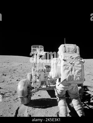 Apollo 16 Mondmission. Dieses Foto, das während der zweiten Extravehicular-Aktivität der Mission aufgenommen wurde, zeigt Astronaut John W. Young, wie er Werkzeuge aus dem Hand-Werkzeugträger des Lunar Roving Vehicle zurückgeholt hat. Das Marshall Space Flight Center der NASA entwarf, entwickelte und verwaltete die Produktion des Mondrovers und der Saturn-V-Rakete, die Astronauten zum Mond brachte. 20. April 1972. Ein einzigartiges, optimiertes NASA-Bild (mit zusätzlichem schwarzen vertikalen Raum über dem ursprünglichen quadratischen Bild): Quelle: NASA ein optimiertes NASA-Bild: Quelle: NASA Stockfoto