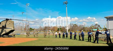 Soldaten der Florida Army National Guard und Notfallteams im gesamten Bundesstaat Florida entladen einen Boeing CH-47 Chinook-Hubschrauber der US Army während der Notfallmaßnahmen des US-amerikanischen Heeres Ian in Pine Island, Florida 3. Oktober 2022. Der Hubschrauber lieferte Nahrung und Wasser für die Einsatzenden in Pine Island und verteilte es an die Bewohner, die von der Zerstörung durch den Herküchen Ian betroffen waren. (Foto der Nationalgarde der Florida Army von Staff Sgt. Cassandra Vieira) Stockfoto