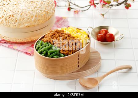 Sanshoku Lunchbox, dreifarbige japanische Reisjunchbox mit geschmorntem Rindfleisch, gekochten französischen Bohnen und Rühreiern. Stockfoto