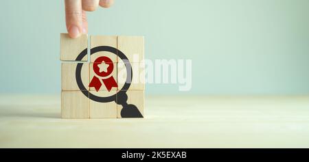 Qualitätsgarantie-Konzept. Standardisierung, ISO. Handplatzierte Holzwürfel mit Qualitätsgarantie-Symbol auf grauem Hintergrund.wird für Banner und Werbung verwendet Stockfoto