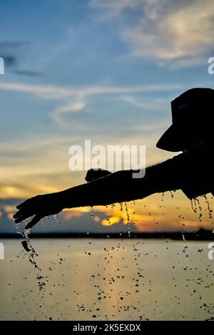 Ein Wasserballon platzt vor einem Sonnenuntergangshimmel. Stockfoto