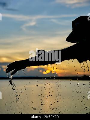 Ein Wasserballon platzt vor einem Sonnenuntergangshimmel. Stockfoto