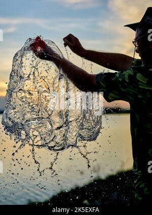 Ein Wasserballon platzt vor einem Sonnenuntergangshimmel. Stockfoto