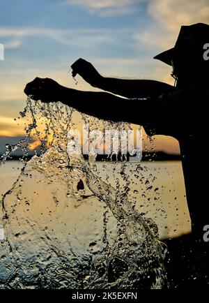 Ein Wasserballon platzt vor einem Sonnenuntergangshimmel. Stockfoto