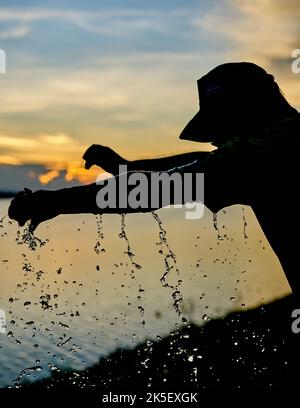 Ein Wasserballon platzt vor einem Sonnenuntergangshimmel. Stockfoto