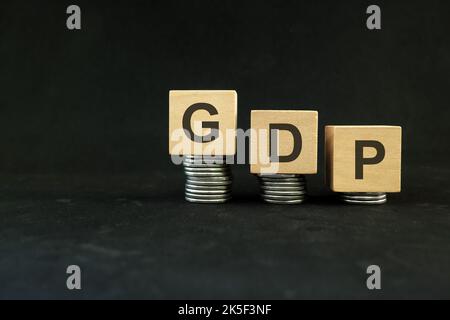Krisenkonzept für das BIP oder das Bruttoinlandsprodukt nach Fälligkeit. Holzblöcke auf dunkelschwarzem Hintergrund. Stockfoto