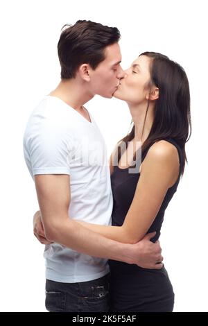 Wahre Liebe zeigen. Ein glückliches junges Paar, das sich umarmt und küsst, während es auf Weiß isoliert ist. Stockfoto