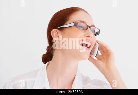 Das ist urkomisch. Eine junge Frau, die am Telefon redet und lacht. Stockfoto