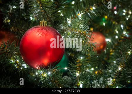 Auf dem Ast des grünen Weihnachtsbaums hängt Weihnachtsspielzeug in der Form Ball aus rot auf einem grünen Hintergrund. weihnachten Hintergrund. Rosa Kugel auf einem Chr. Stockfoto