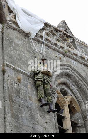 Sainte-Mere-Eglise, FRA, Frankreich - 21. August 2022: Fallschirmjäger-Schaufensterpuppe, die vom Kirchturm hängt Stockfoto