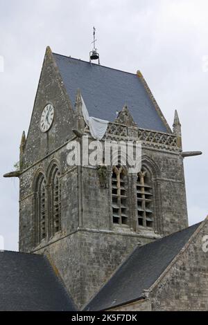 Sainte-Mere-Eglise, FRA, Frankreich - 21. August 2022: Fallschirmjäger-Schaufensterpuppe, die vom Kirchturm hängt Stockfoto